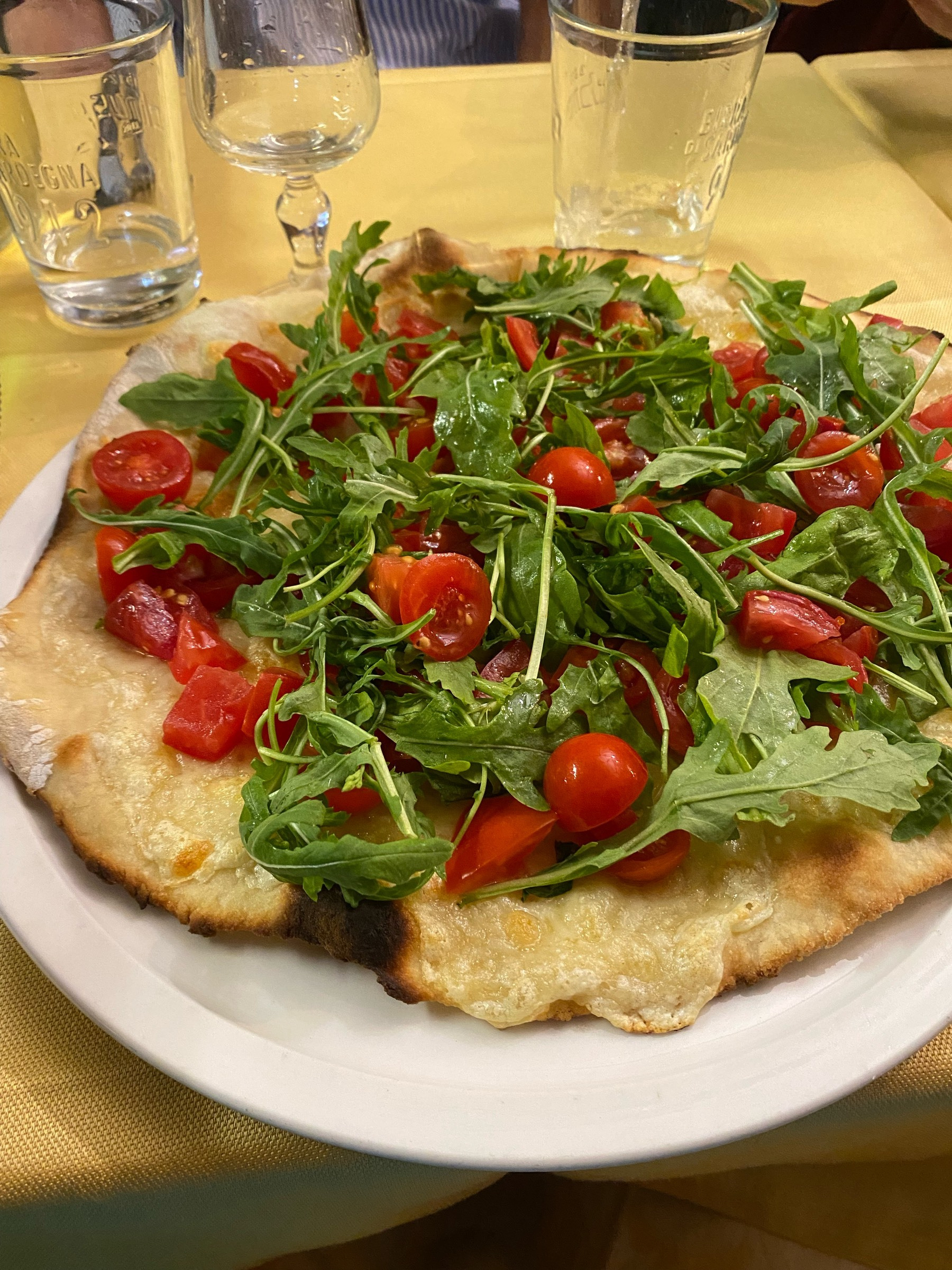 A pizza with vibrant red cherry tomatoes and green rocket leaves. 