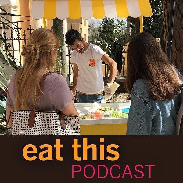 Auto-generated description: Two people with long hair are watching a man prepare food at an outdoor stand, with the text eat this PODCAST below.