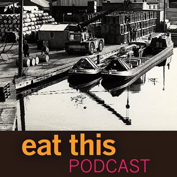 Auto-generated description: A vintage photograph depicts a waterfront scene with two barges on a canal, surrounded by industrial buildings, and features the text eat this PODCAST in large, bold letters at the bottom.