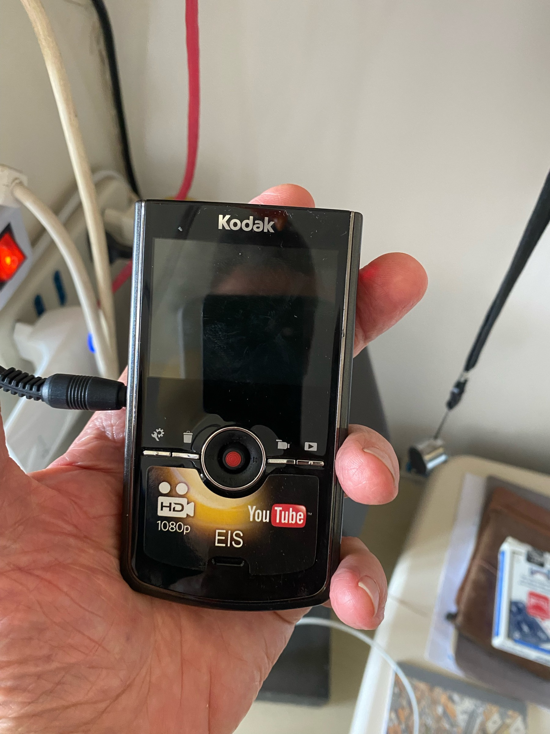 A Small handheld video camera similar in shape to a phone with a screen and control buttons beneath the screen. 