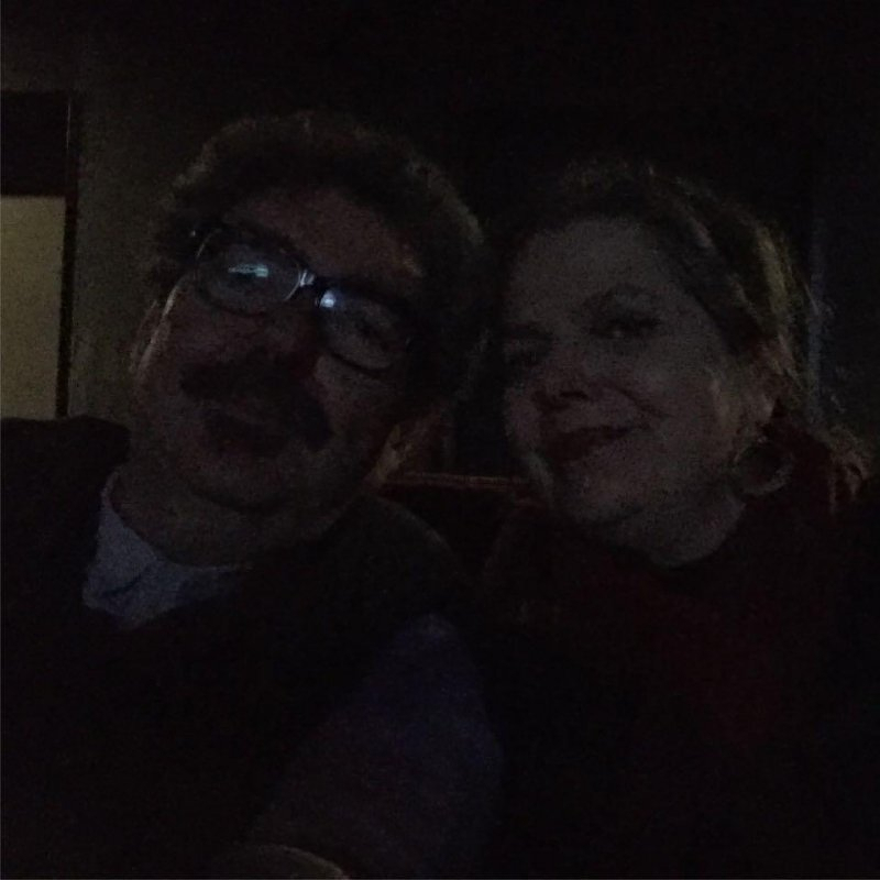 Auto-generated description: Two people are sitting together in a dimly lit setting.