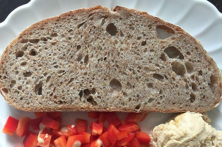 Auto-generated description: A slice of bread on a plate is accompanied by chopped red peppers and a serving of hummus.