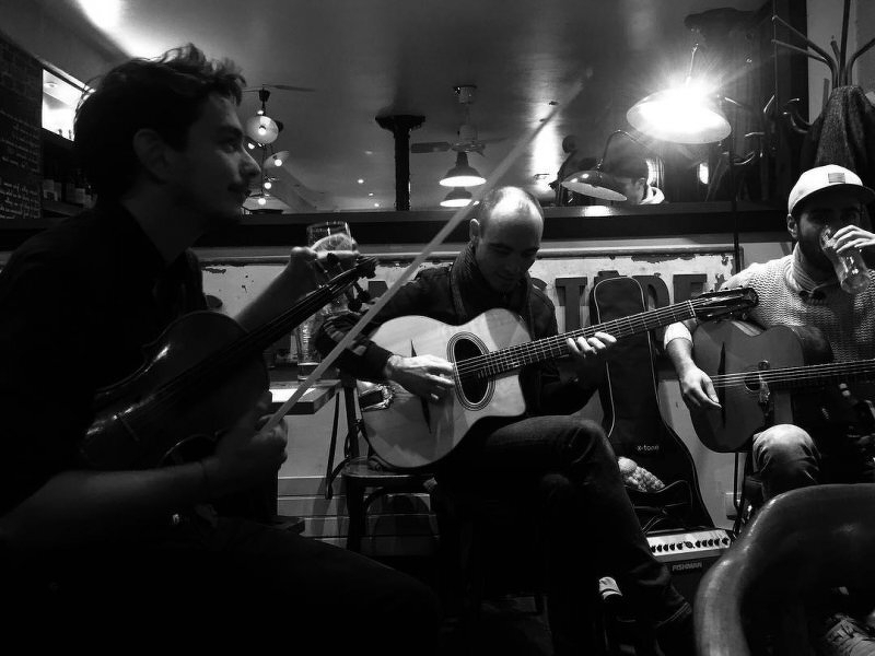 Monochrome image of two men playing guitars in a cafe in Paris