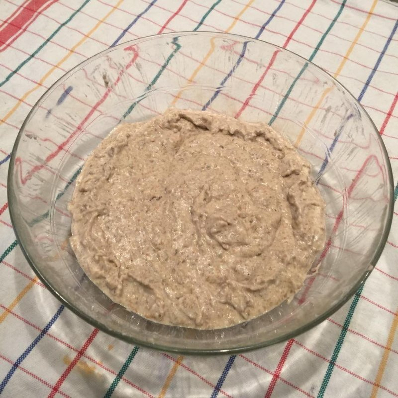 Auto-generated description: A glass bowl filled with a beige, coarse mixture sits on a checkered tablecloth.