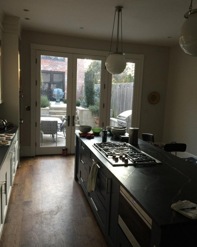 A kitchen with an island unit ready with bowls and scales, in front of large glass doors.