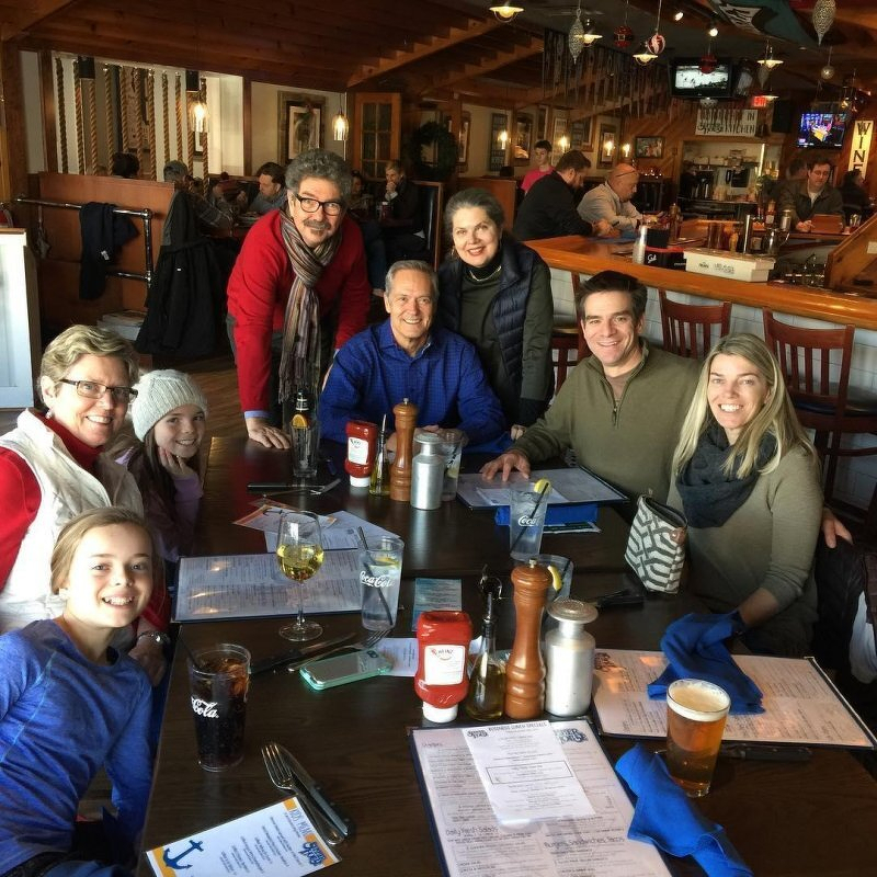 Auto-generated description: A group of people is gathered around a table at a restaurant, smiling for the camera.